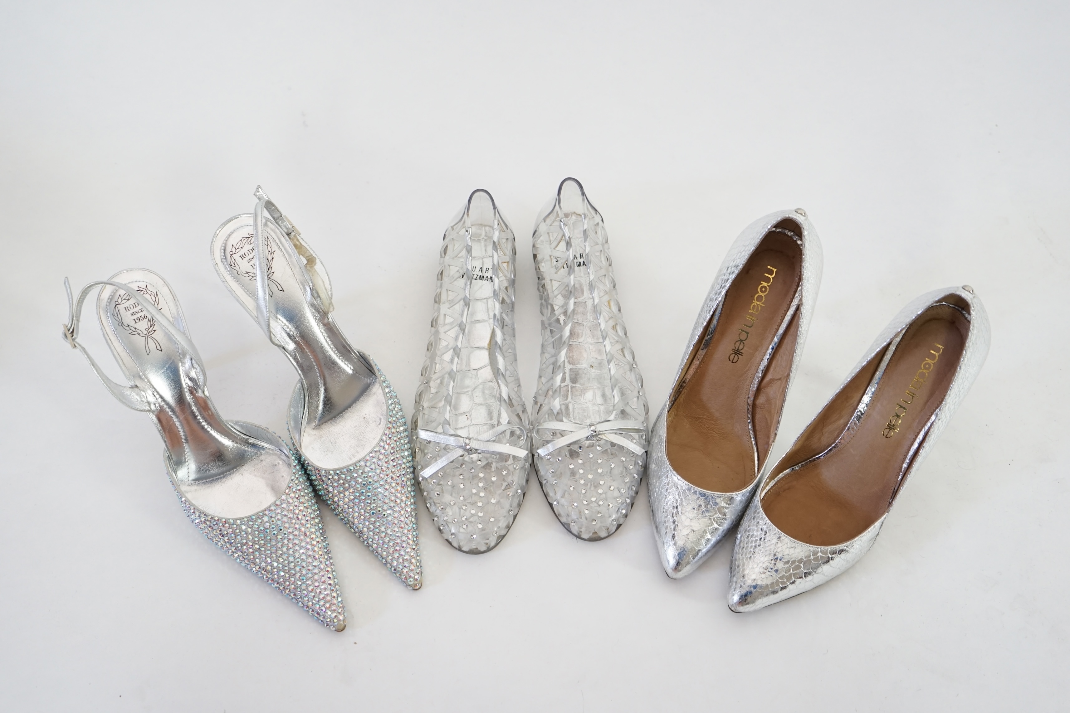 Three pairs of lady's silver shoes: Rodo silver diamonté sling back heels, Moda in Pelle silver snakeskin pattern heeled pumps and a pair of Stuart Weitzman clear jelly's with crystals. Size 38.5 (UK 4). Proceeds to Happ